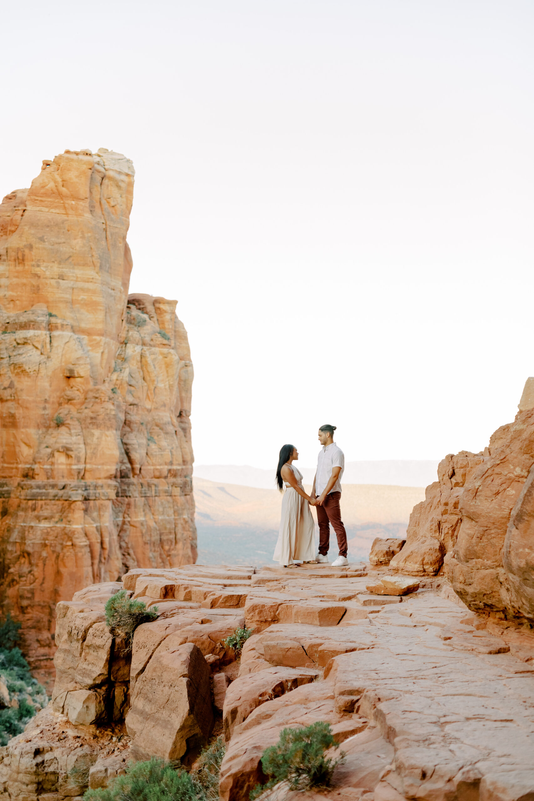 Photo of Lakin and Jasmyne at Sunrise:
"Lakin and Jasmyne stand together on top of Cathedral Rock in Sedona at sunrise, with the warm, golden light highlighting their joyful expressions and the stunning red rock formations in the background."