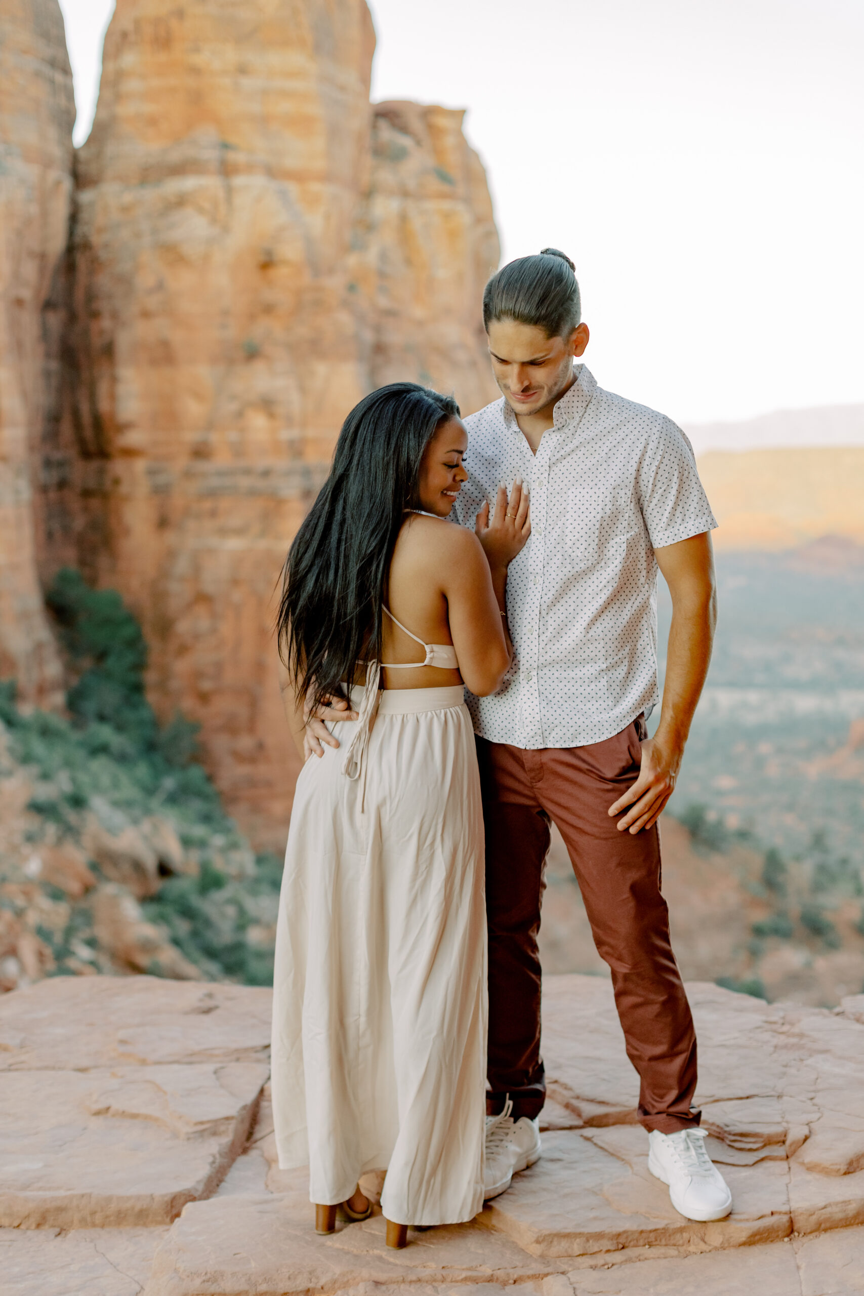 Photo of Lakin and Jasmyne at Sunrise:
"Lakin and Jasmyne stand together on top of Cathedral Rock in Sedona at sunrise, with the warm, golden light highlighting their joyful expressions and the stunning red rock formations in the background."