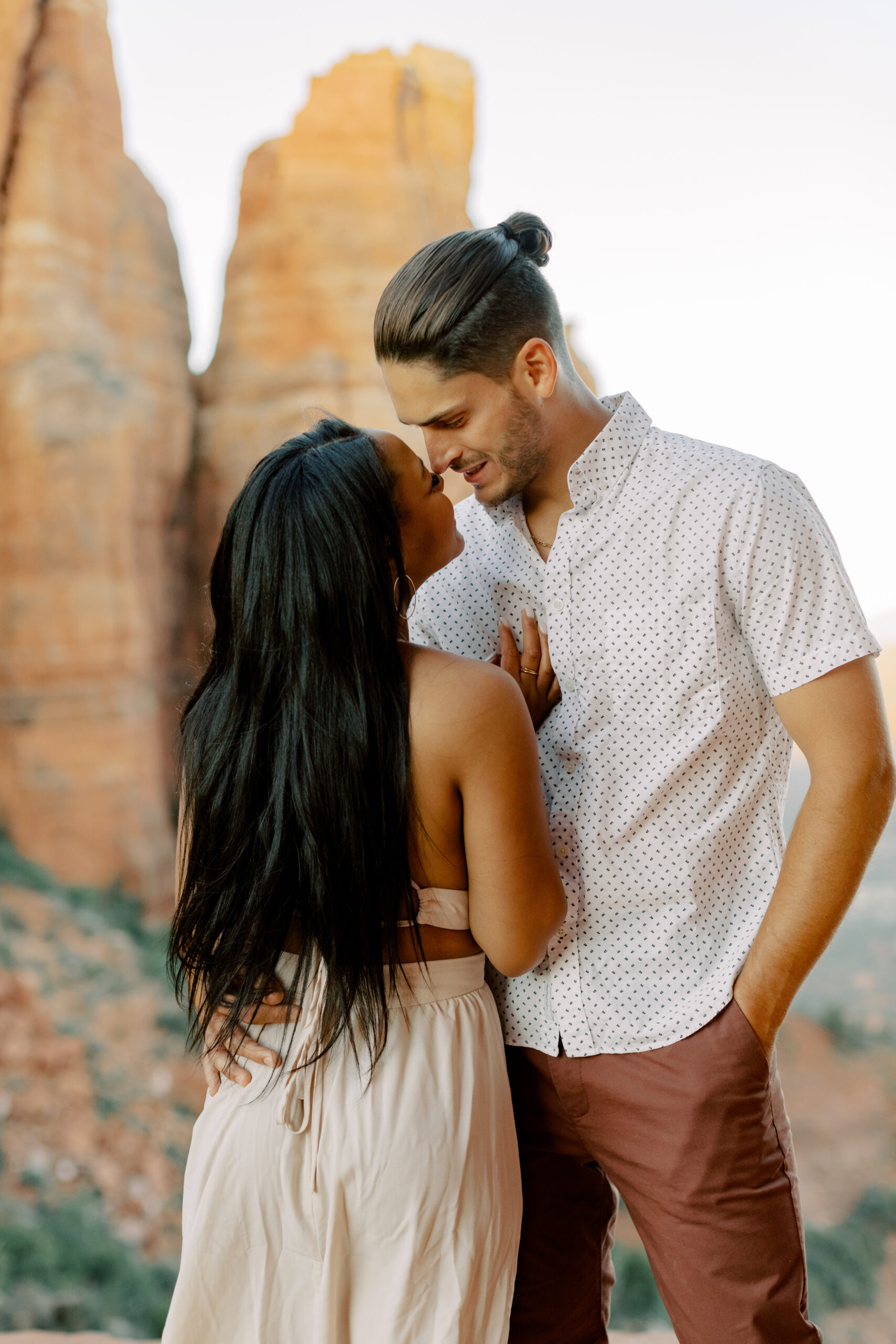 Close-Up of Lakin and Jasmyne Embracing:
"A close-up shot of Lakin and Jasmyne embracing, with their foreheads touching and eyes closed, capturing an intimate and tender moment with the vibrant Sedona sunrise behind them."