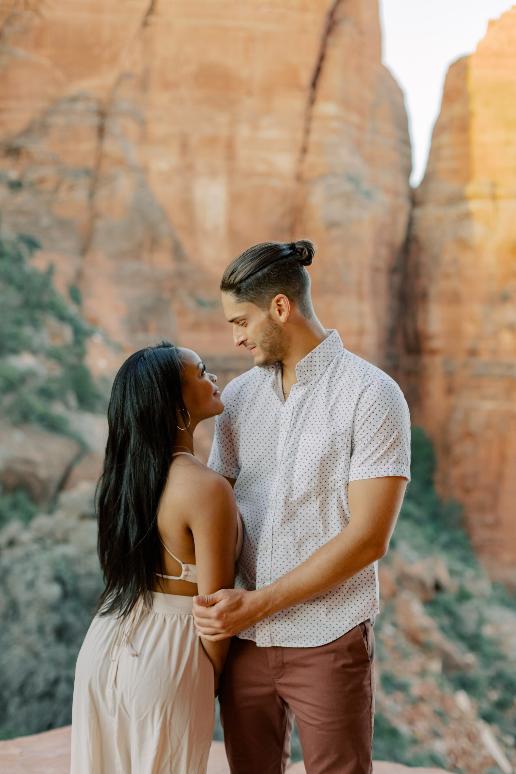 Photo of Lakin and Jasmyne at Sunrise:
"Lakin and Jasmyne stand together on top of Cathedral Rock in Sedona at sunrise, with the warm, golden light highlighting their joyful expressions and the stunning red rock formations in the background."