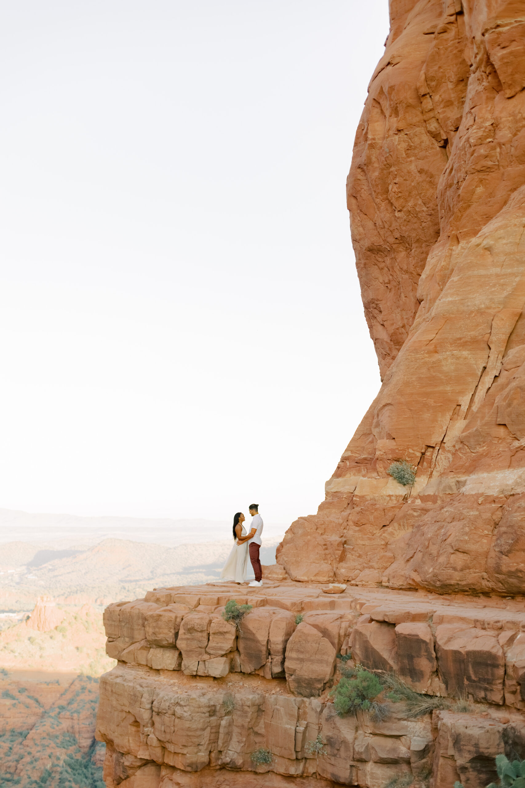 Photo of Lakin and Jasmyne at Sunrise:
"Lakin and Jasmyne stand together on top of Cathedral Rock in Sedona at sunrise, with the warm, golden light highlighting their joyful expressions and the stunning red rock formations in the background."