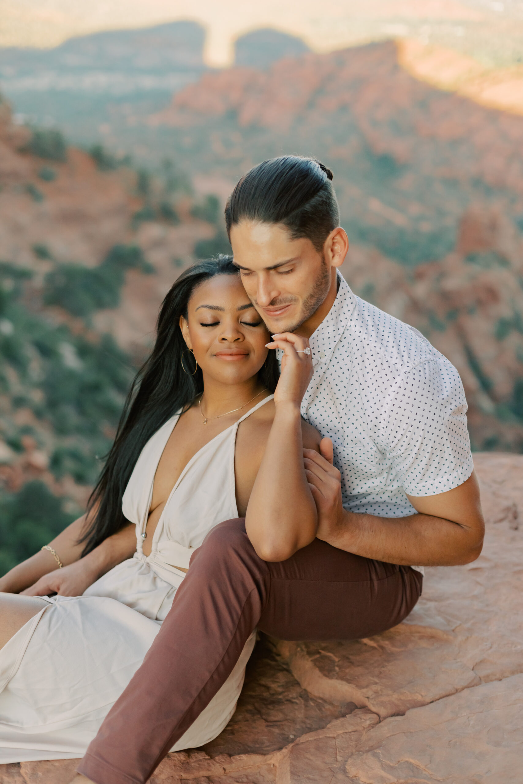 Photo of Lakin and Jasmyne at Sunrise:
"Lakin and Jasmyne stand together on top of Cathedral Rock in Sedona at sunrise, with the warm, golden light highlighting their joyful expressions and the stunning red rock formations in the background."