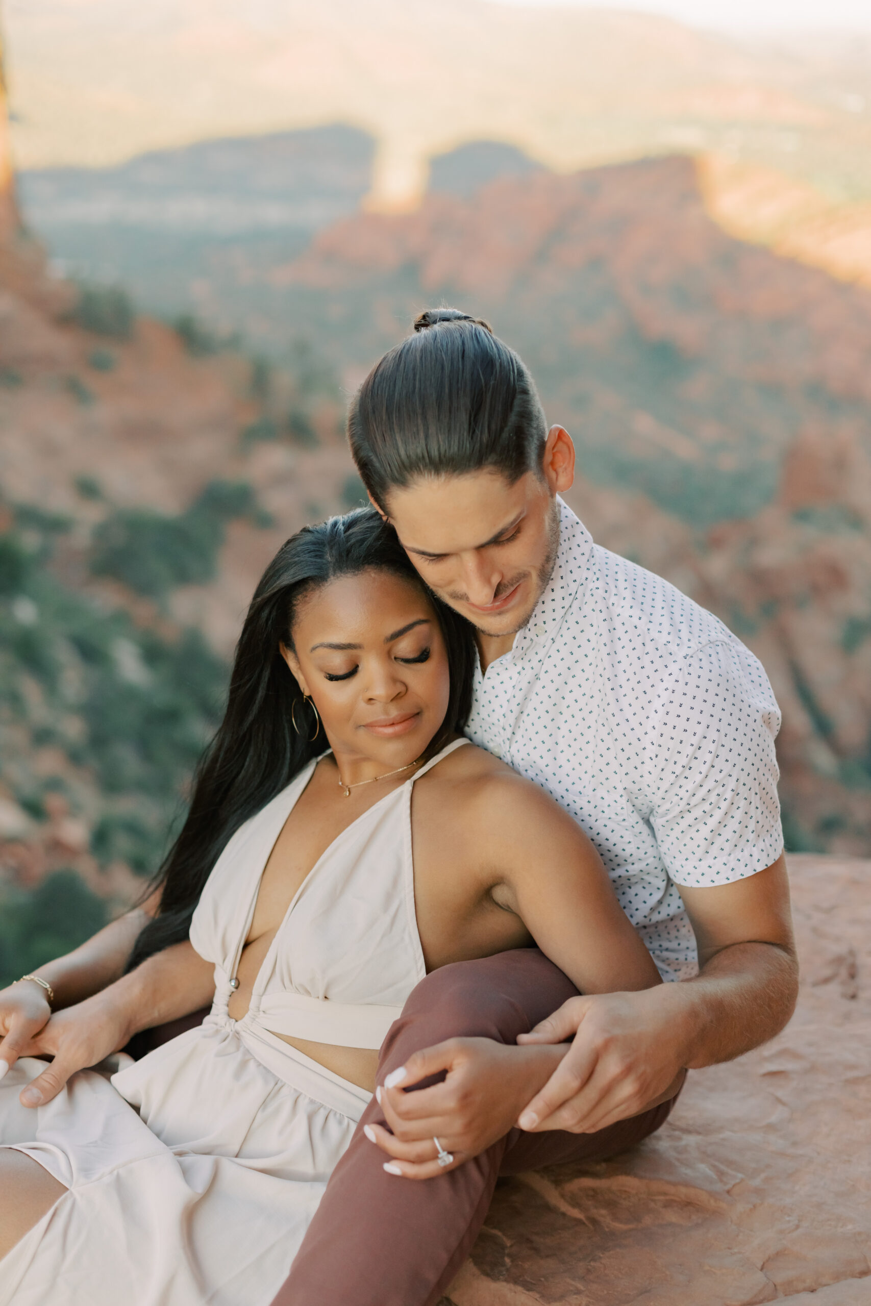 Photo of Lakin and Jasmyne at Sunrise:
"Lakin and Jasmyne stand together on top of Cathedral Rock in Sedona at sunrise, with the warm, golden light highlighting their joyful expressions and the stunning red rock formations in the background."