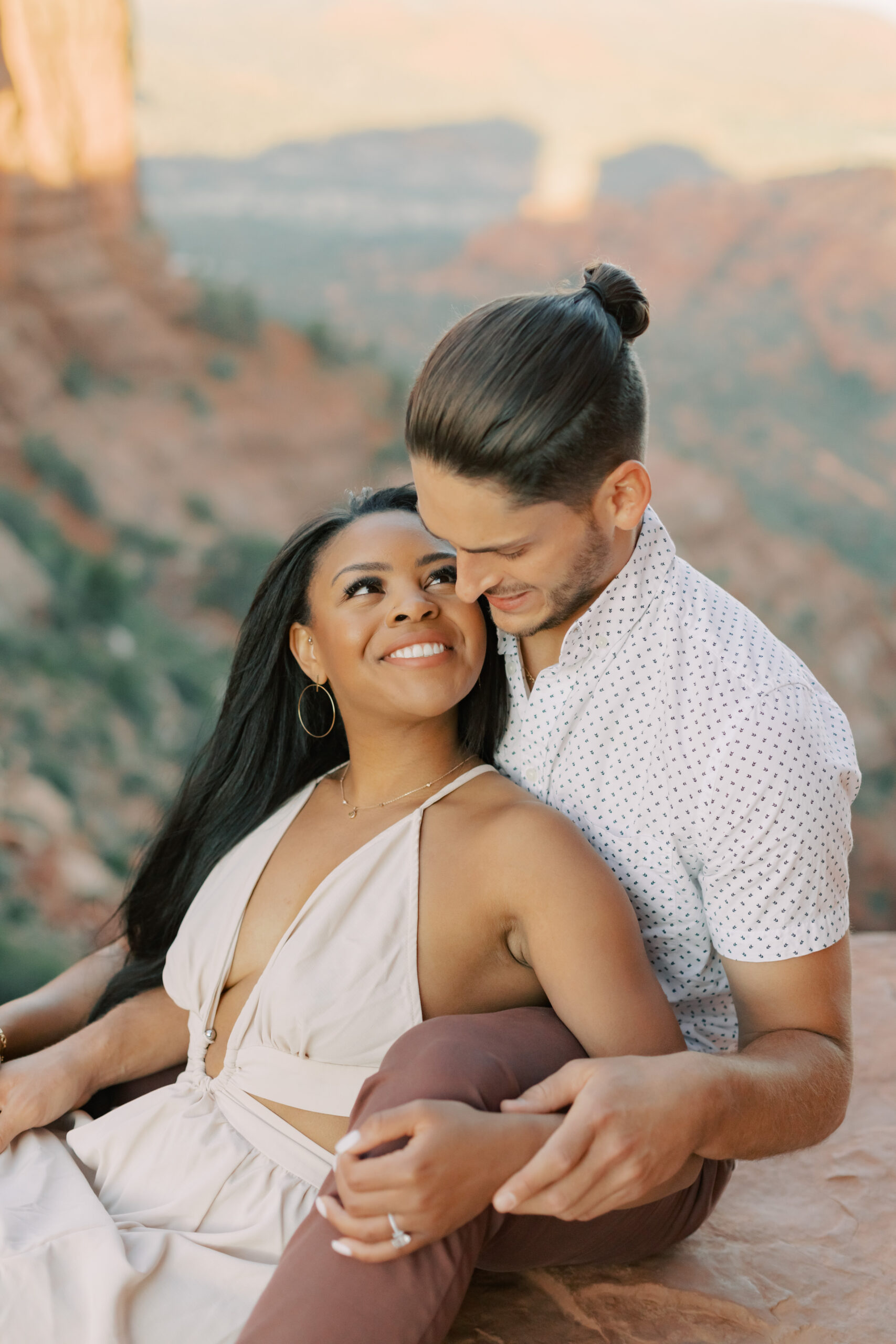 Photo of Lakin and Jasmyne at Sunrise:
"Lakin and Jasmyne stand together on top of Cathedral Rock in Sedona at sunrise, with the warm, golden light highlighting their joyful expressions and the stunning red rock formations in the background."