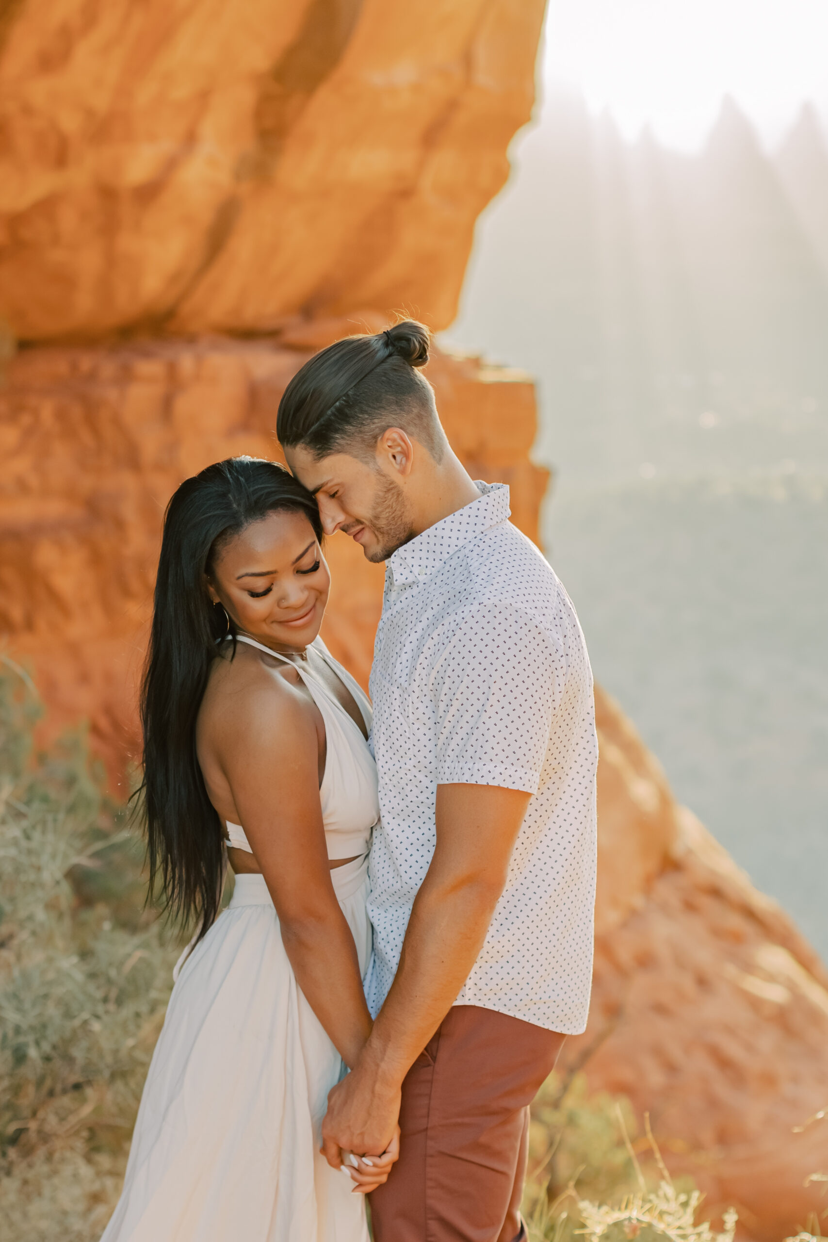 Photo of Lakin and Jasmyne at Sunrise:
"Lakin and Jasmyne stand together on top of Cathedral Rock in Sedona at sunrise, with the warm, golden light highlighting their joyful expressions and the stunning red rock formations in the background."