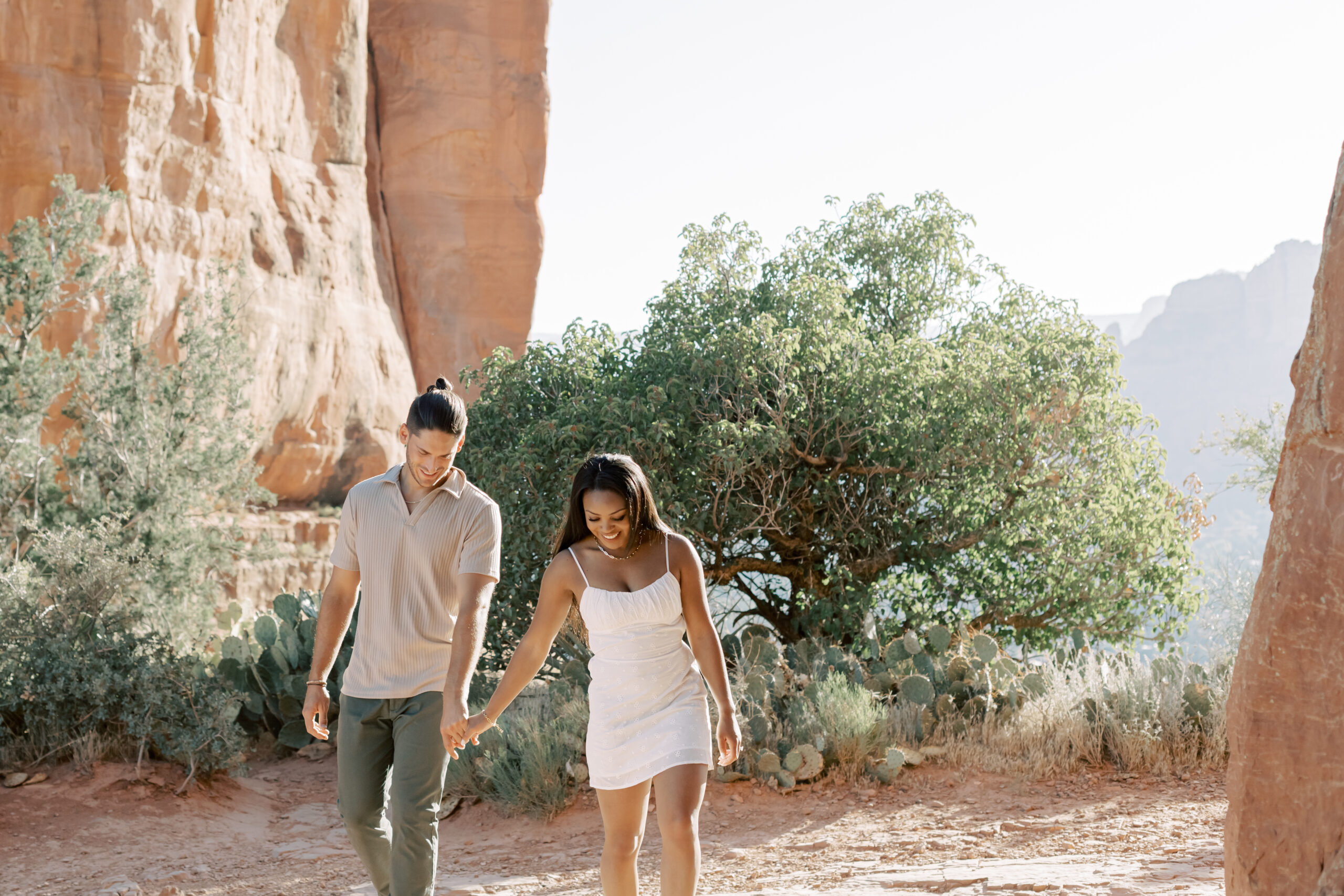 Photo of Lakin and Jasmyne at Sunrise:
"Lakin and Jasmyne stand together on top of Cathedral Rock in Sedona at sunrise, with the warm, golden light highlighting their joyful expressions and the stunning red rock formations in the background."