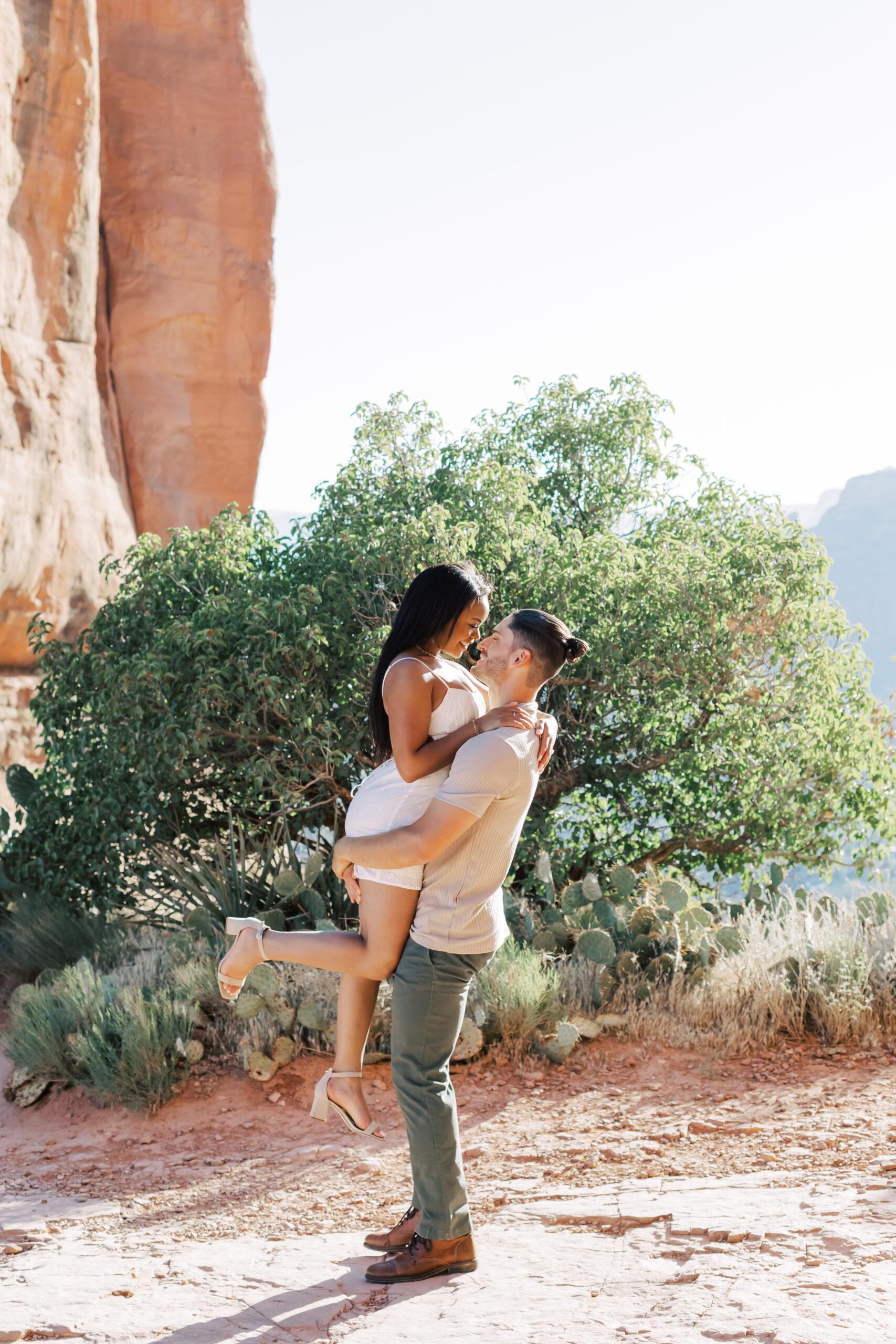 Photo of Lakin and Jasmyne at Sunrise:
"Lakin and Jasmyne stand together on top of Cathedral Rock in Sedona at sunrise, with the warm, golden light highlighting their joyful expressions and the stunning red rock formations in the background."