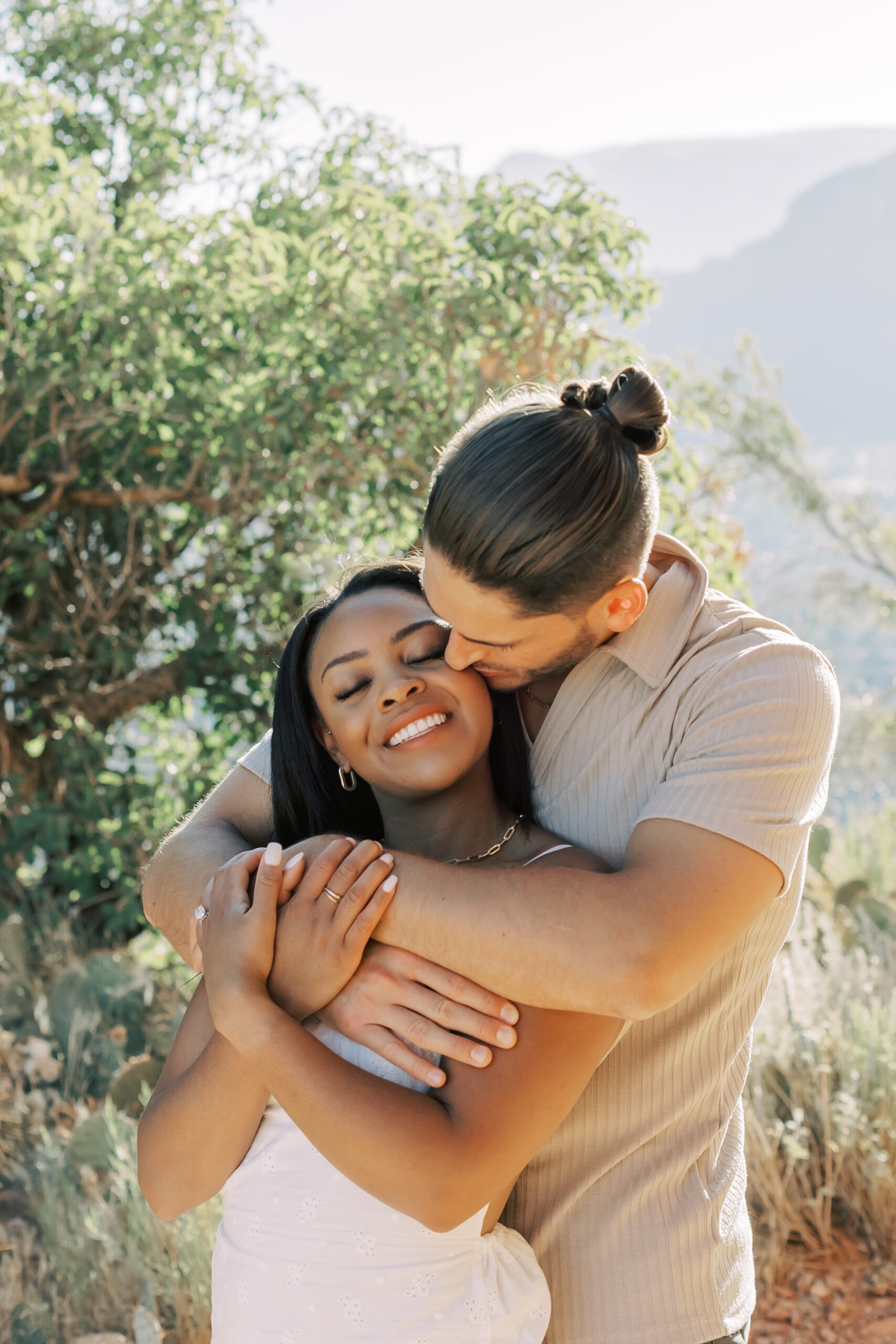 Photo of Lakin and Jasmyne at Sunrise:
"Lakin and Jasmyne stand together on top of Cathedral Rock in Sedona at sunrise, with the warm, golden light highlighting their joyful expressions and the stunning red rock formations in the background."