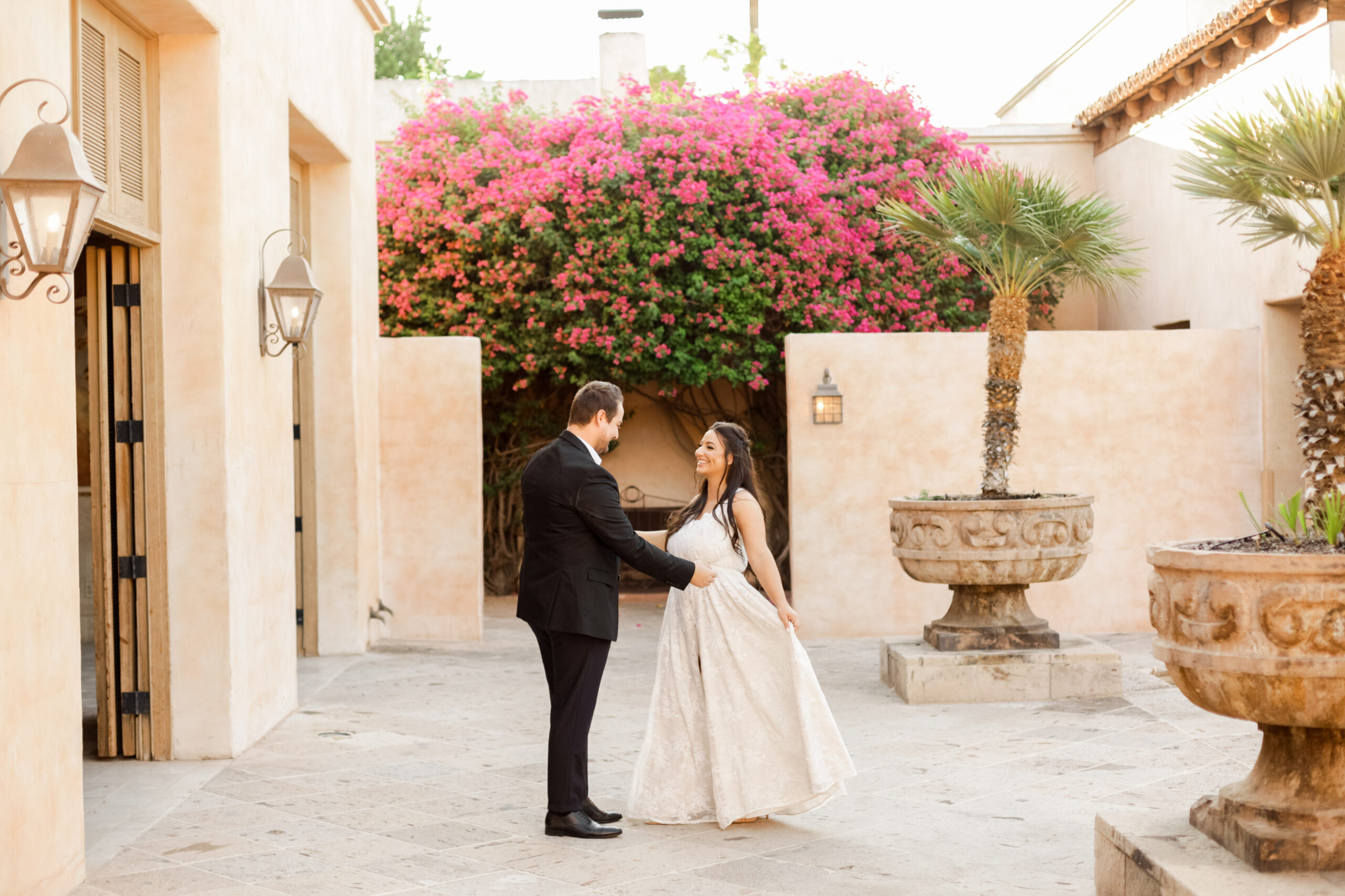 A bride and groom dance at Scottsdale's leading luxury wedding venue, Royal Palms Resort and Spa. The venue features inviting Mediterranean ambience and the bride and groom are beaming at each other with joy.